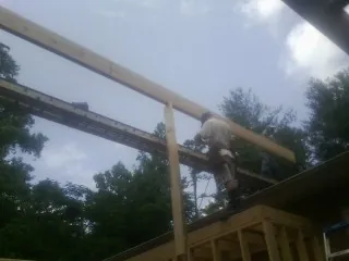 Carpenter setting a ridge beam over a new addition frame — Ice Dam Removal by Roofing Brothers in Saint Marks