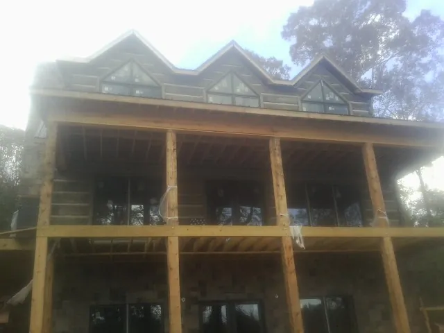 Dormers and porch framing on a large log home under construction — Roof Coating work by our crew in Saint Marks