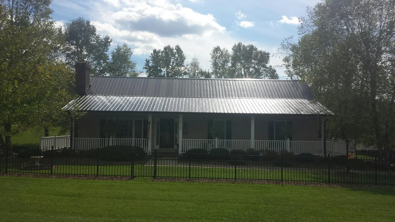 Gray metal roof on a brick ranch with a full width front porch — Gutter Guard Installation work by our crew in Saint Marks