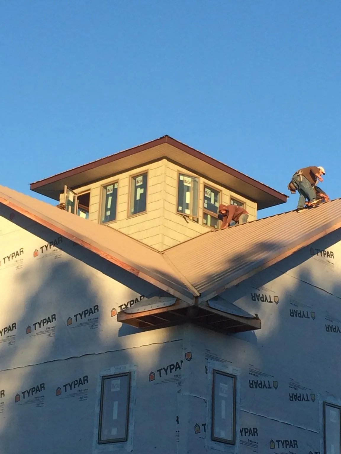 Roofers working around a rooftop cupola on a new metal roof at sunset — Roof Waterproofing in Saint Marks by Roofing Brothers